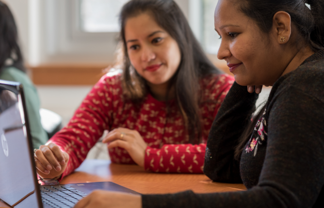 Person helping another person at a laptop