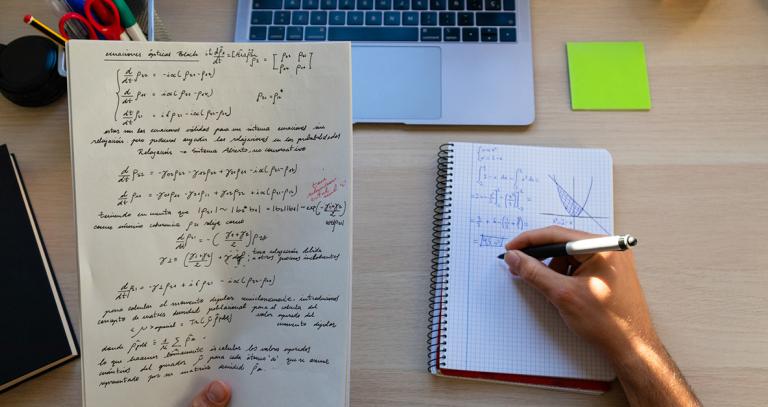 Desk with post-it, laptop, notebook, agenda, and papers