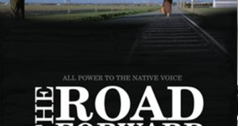 Photo of an Indigenous woman walking away from camera down a prairie road