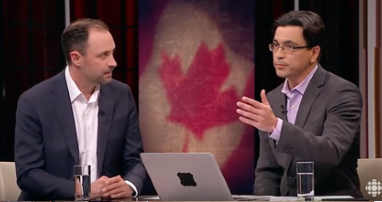 Video still of two men in conversation with the image of a Canadian flag between them.